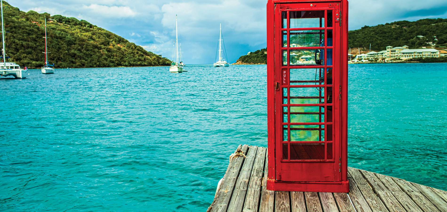 Red telephone booth overlooking the sea and mountainous landscape of the British Virgin Islands.