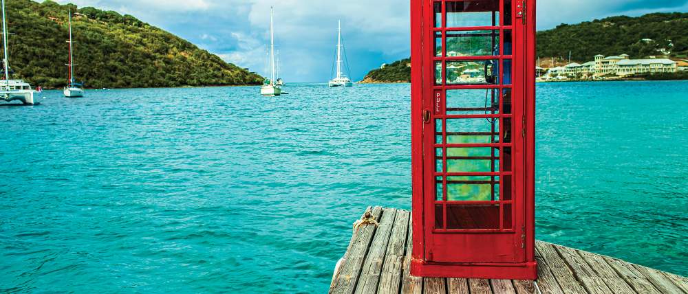 Red telephone booth overlooking the sea and mountainous landscape of the British Virgin Islands.