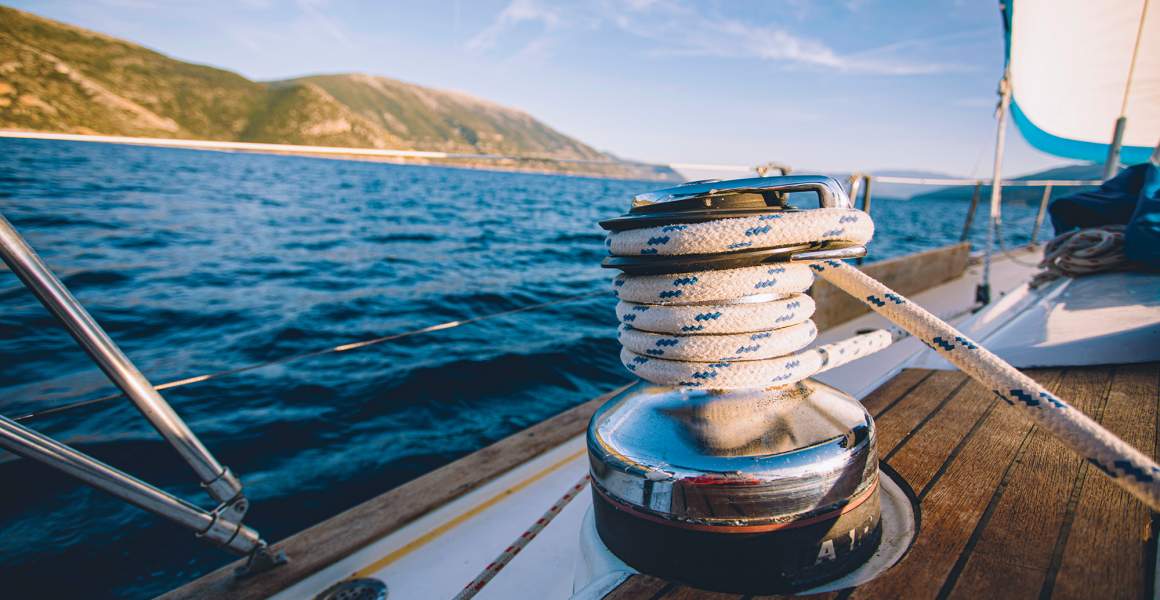 Close-up of sailboat details with the sea and mountains in the background.